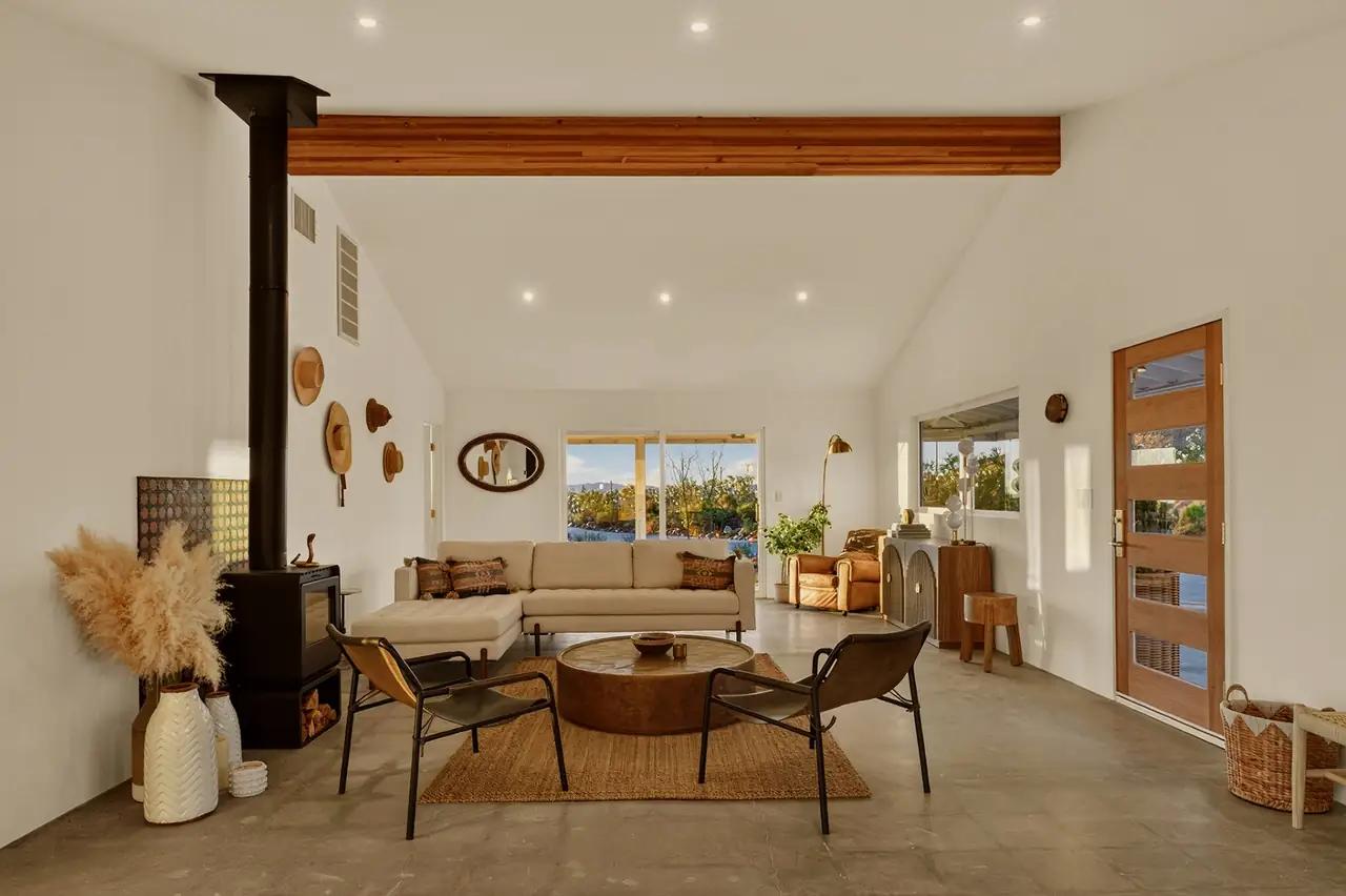 Living room with floor-to-ceiling glass opening to pool and Joshua Trees
