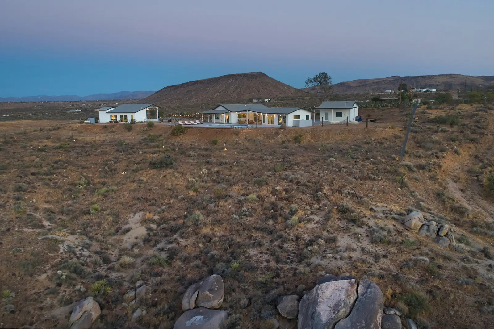 Aerial view of the property at dusk with mountains and desert scrub