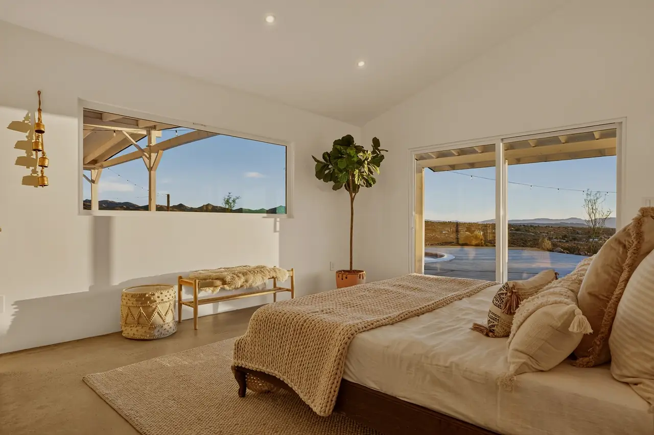 Primary bedroom with pool and mountain views through sliding doors