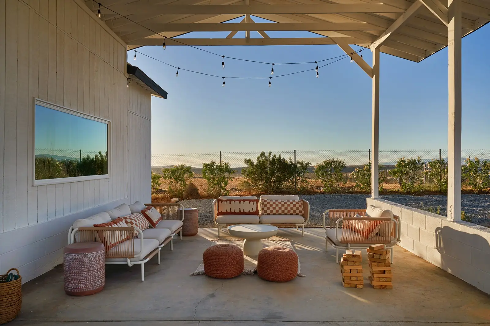 Covered patio lounge with sofas and string lights at golden hour